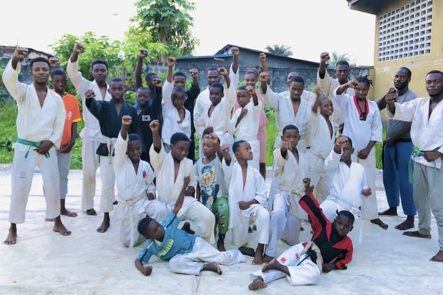 Prunelle Ilunga (kneeling on the far right, behind the athlete in red-black) and his classmates at a Ju-Jitsu martial arts dojo in Kinshasa-DRC, after the test session for passing belts, 2022