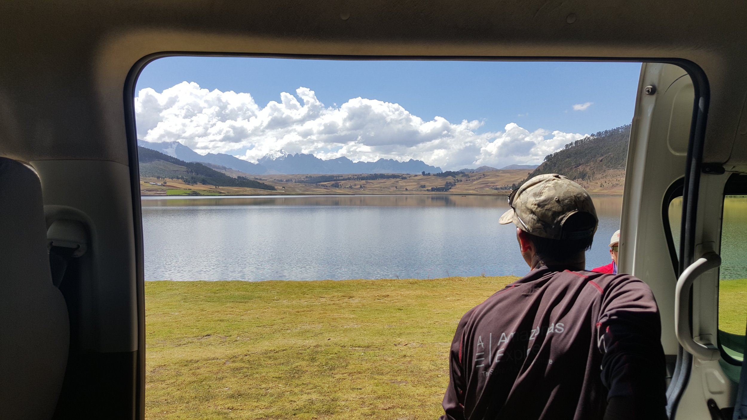 Man looking outside of car at a lake