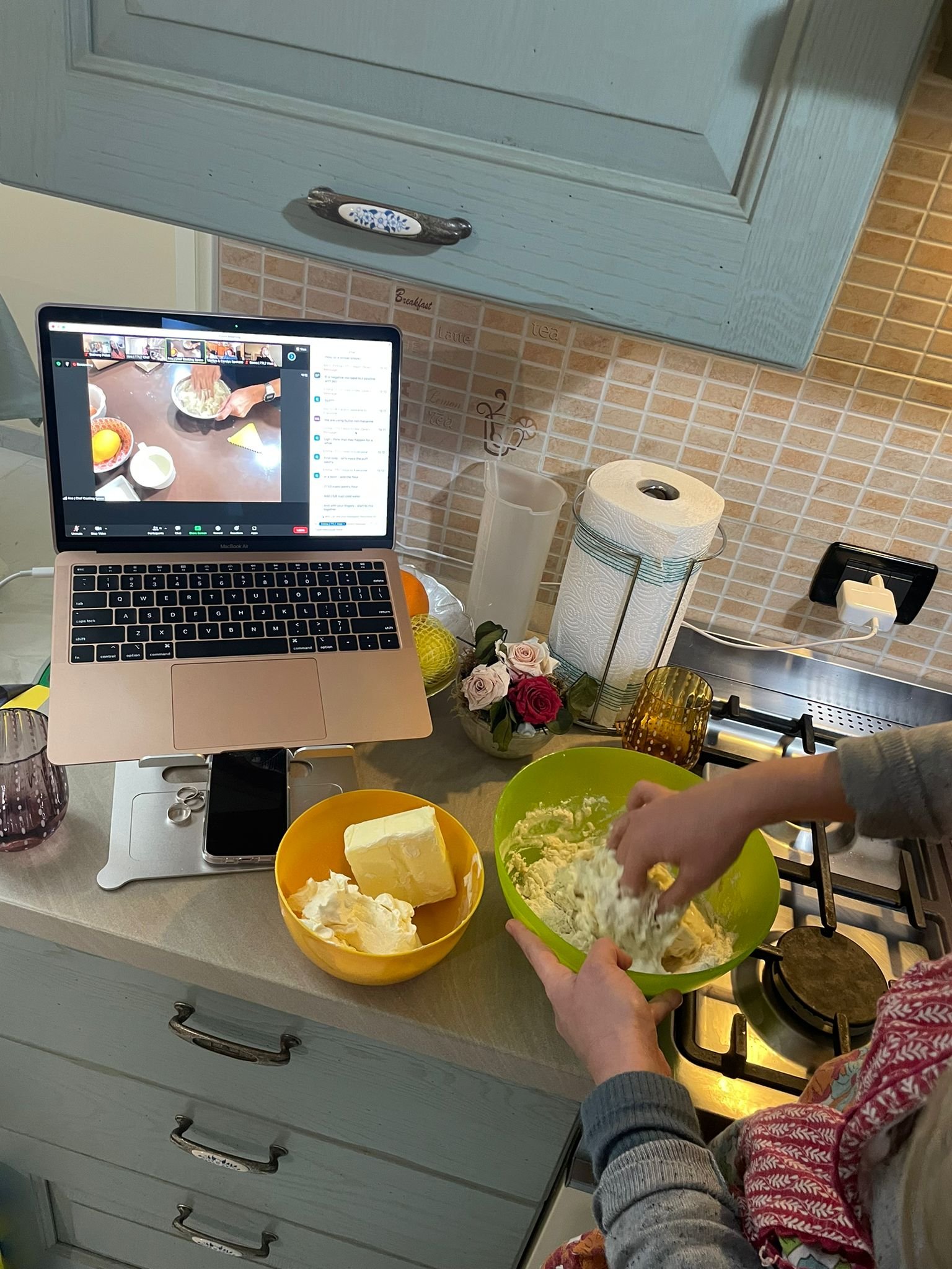 Woman mixing dough while watching demonstration on computer