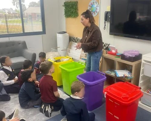 woman in front of set of bins and groups of kids