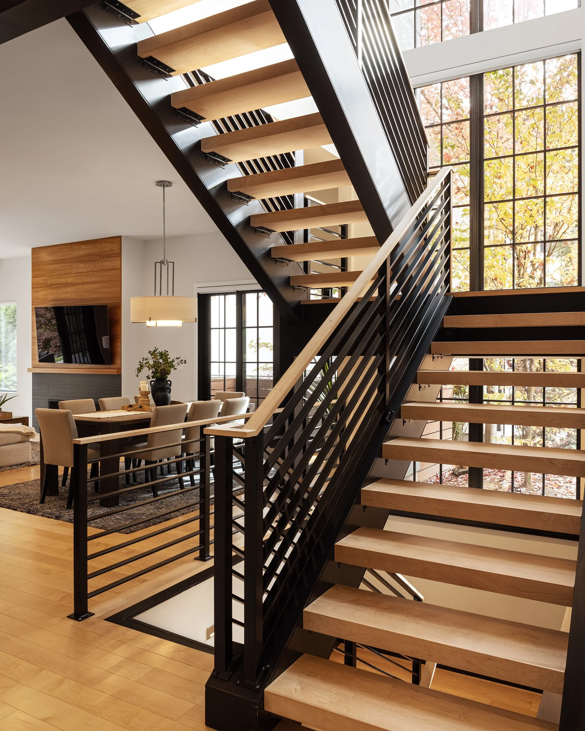 Modern residential interior with open tread wood and steel staircase and dining area, Seattle interior photography by Mike Arty