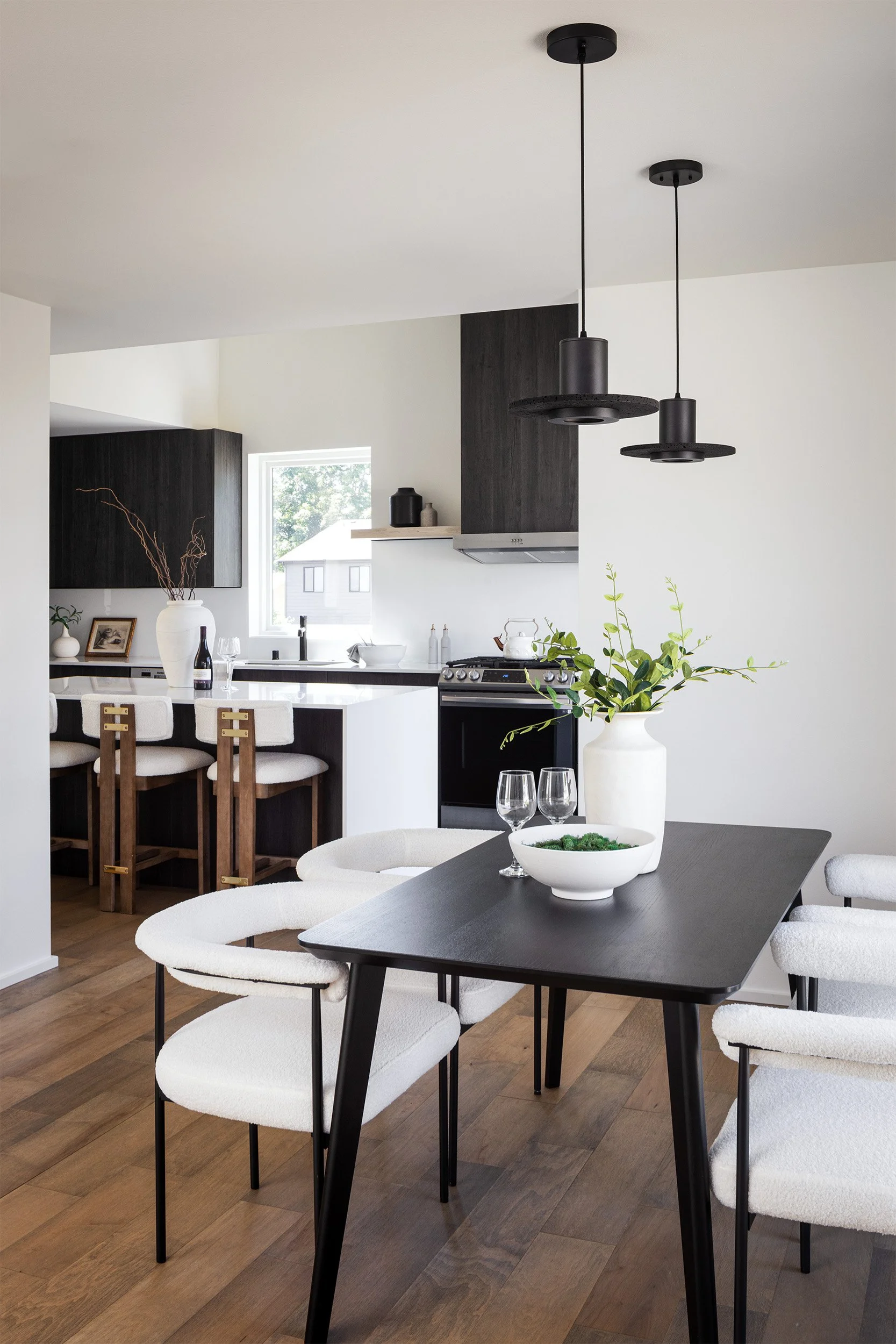 Residential dining and kitchen interior in Seattle with black table, white chairs, and modern black cabinetry, Seattle interior photography by Mike Arty