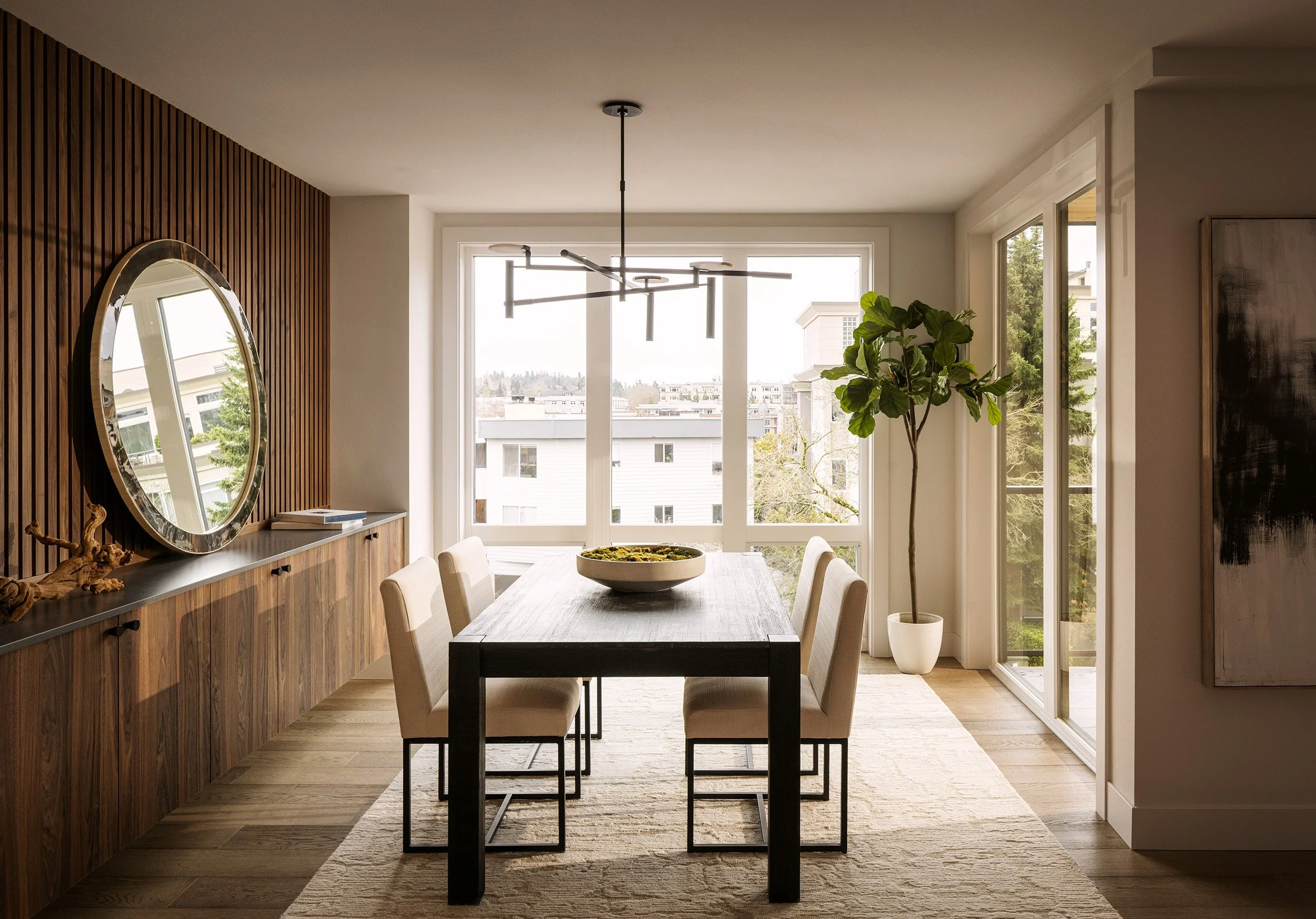 Luxury apartment dining room in Kirkland, WA with large windows, wood slat wall, and modern chandelier
