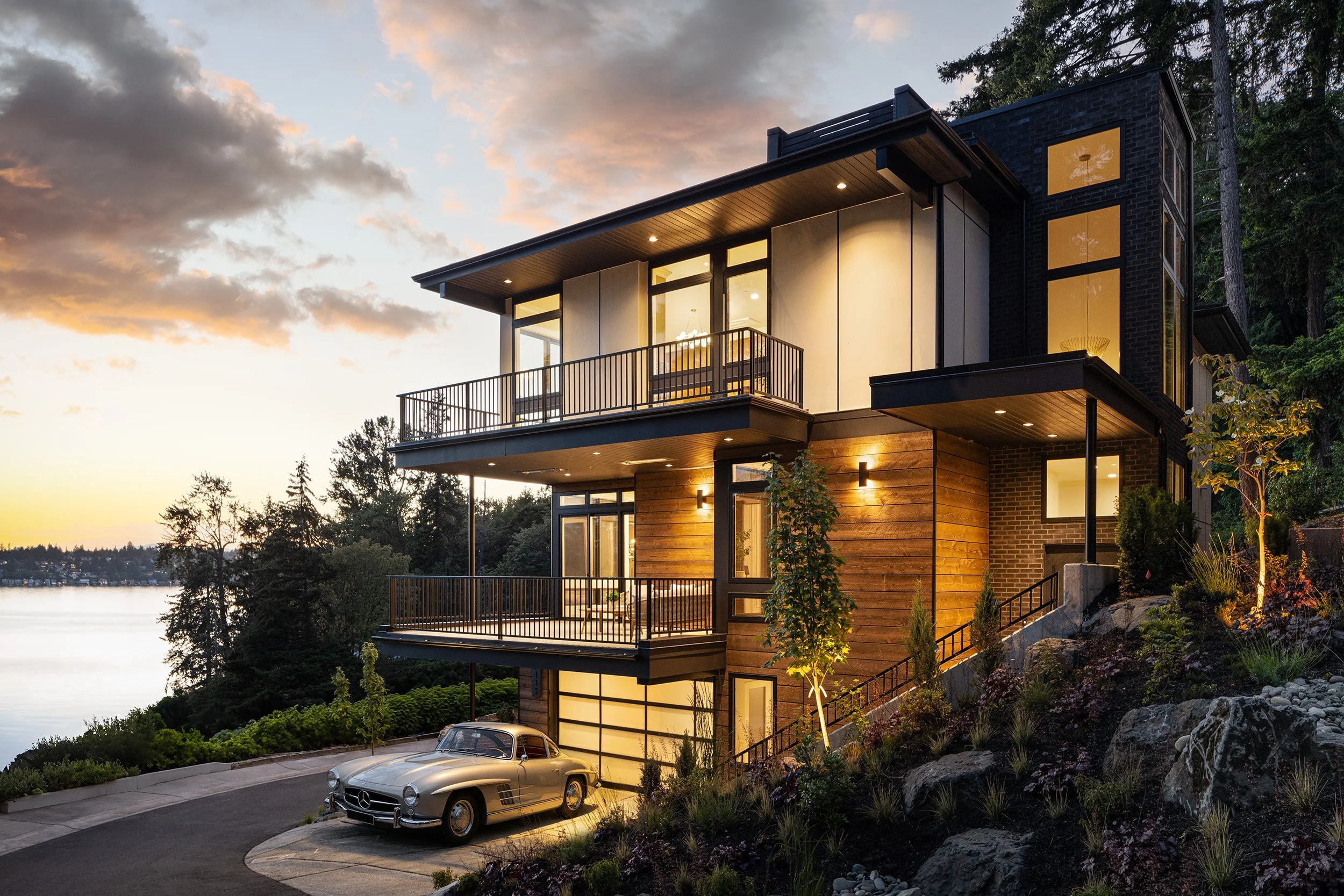 Modern lakeside residential home exterior at dusk with balconies and classic Mercedes in driveway, Seattle architectural photography by Mike Arty