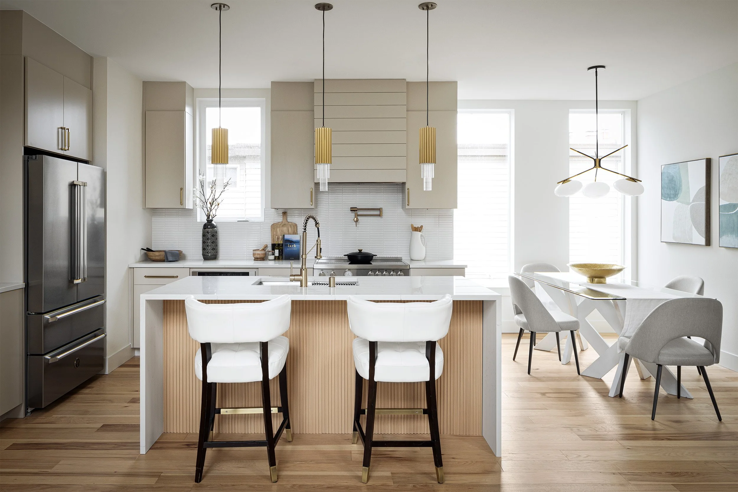 Residential kitchen and dining room interior in Seattle with light cabinetry, island seating, and modern brass pendant lighting, Seattle interior photography by Mike Arty