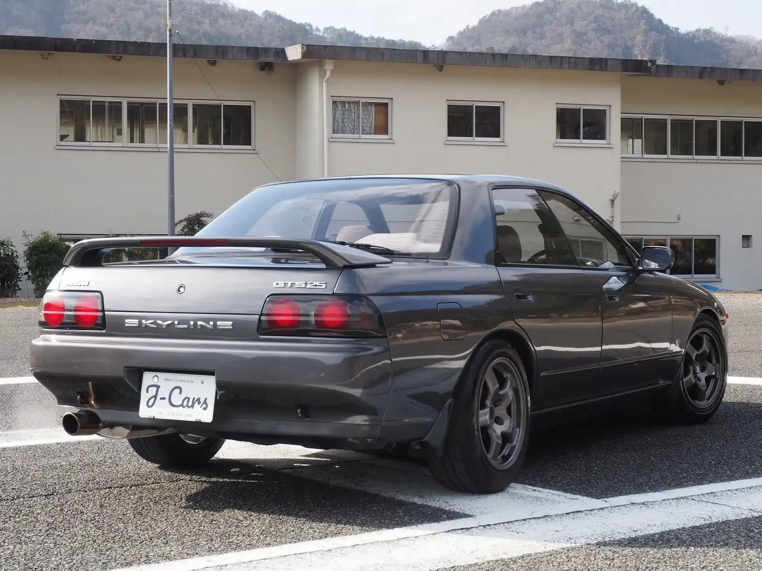 Rear passengers side view of a grey 1991 Nissan Skyline GTS25 Type X G 4 Door Sedan for export from Japan