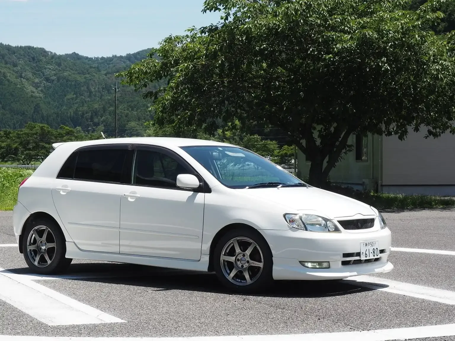drivers corner angle view of white toyota corolla runx aero tourer z 6 speed zze123 with 5 zigen wheels JDM export stock for sale japan