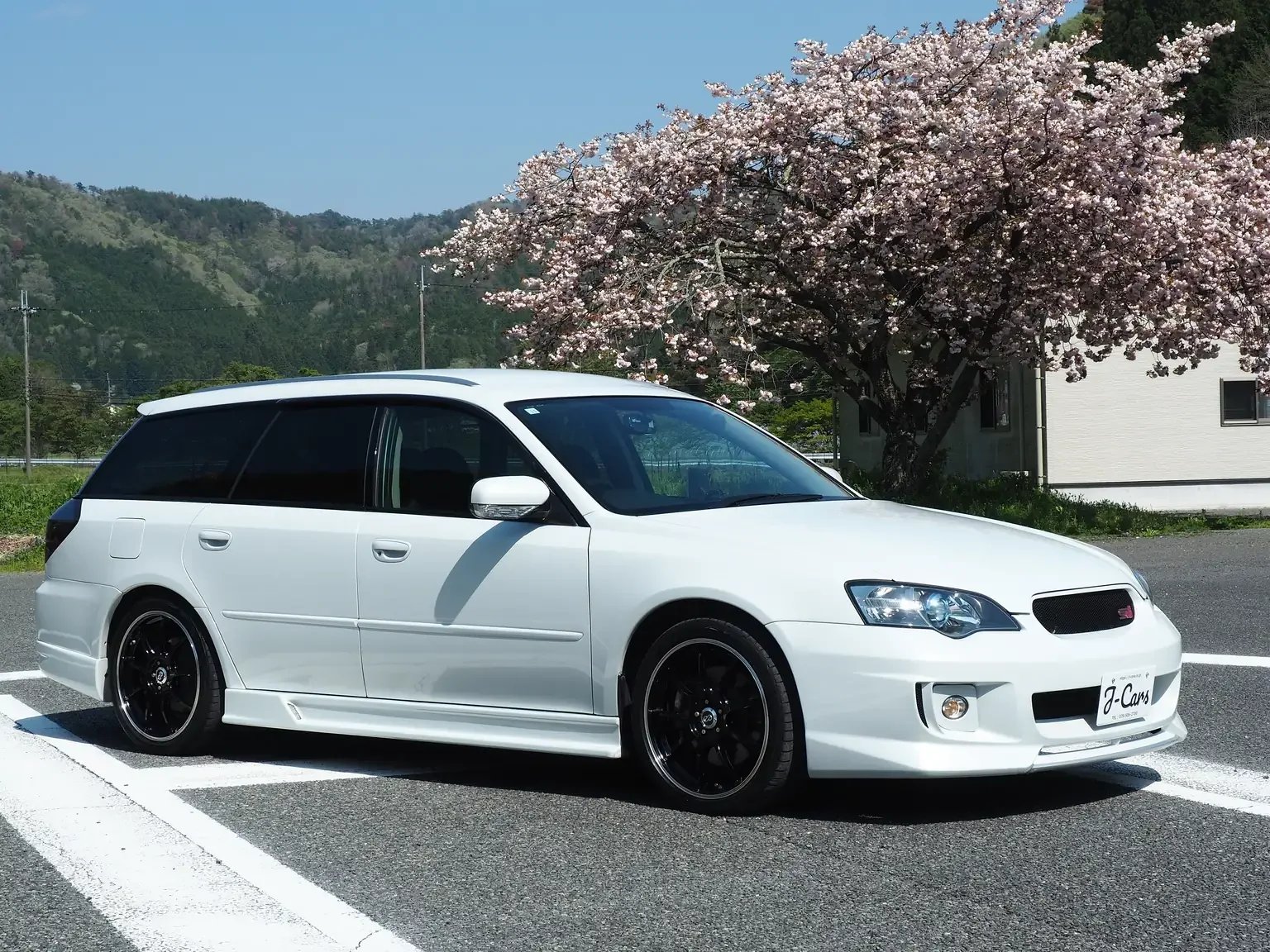 front drivers angle view subaru legacy 3.0R B-Spec 6MT with sakura tree in bloom in the background jdm export stock japan