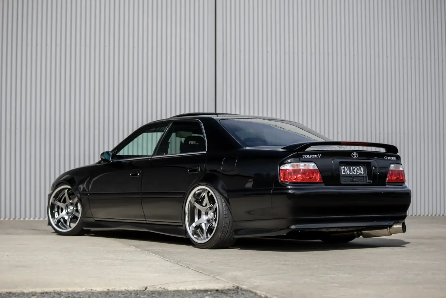 rear passengers angle view black toyota chaser tourer v jzx100 custom steel wide body jdm export vehicle new zealand