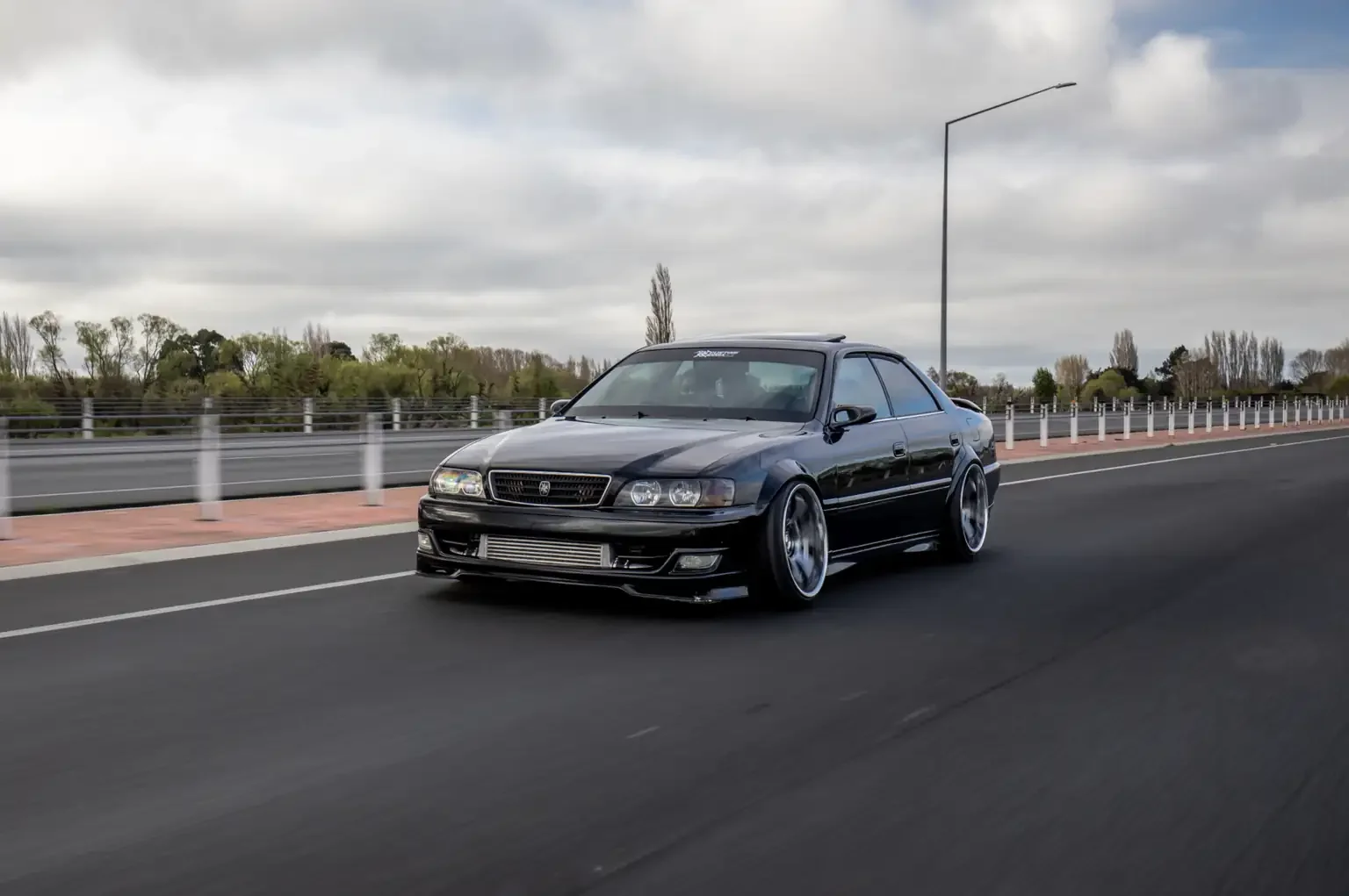 rolling shot on highway view black toyota chaser tourer v jzx100 custom steel wide body jdm export vehicle new zealand