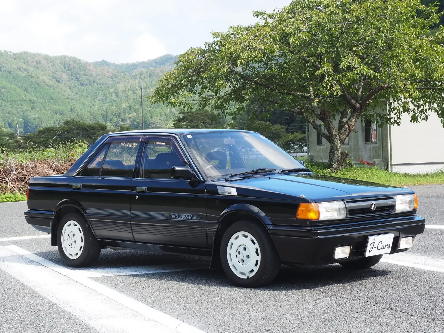 front drivers angle view of black 1989 Nissan sunny super saloon twin cam NISMO in black jdm export vehicle Japan