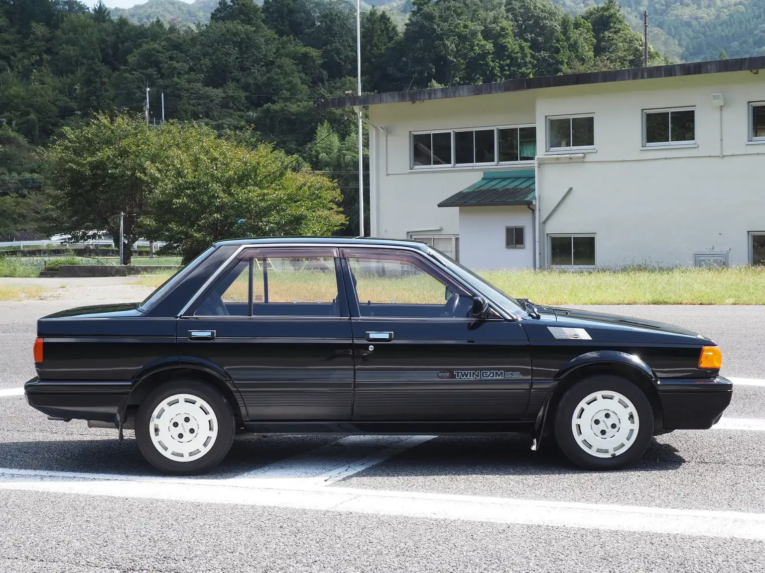 drivers side view of 1989 Nissan sunny super saloon twin cam NISMO in black jdm export vehicle Japan