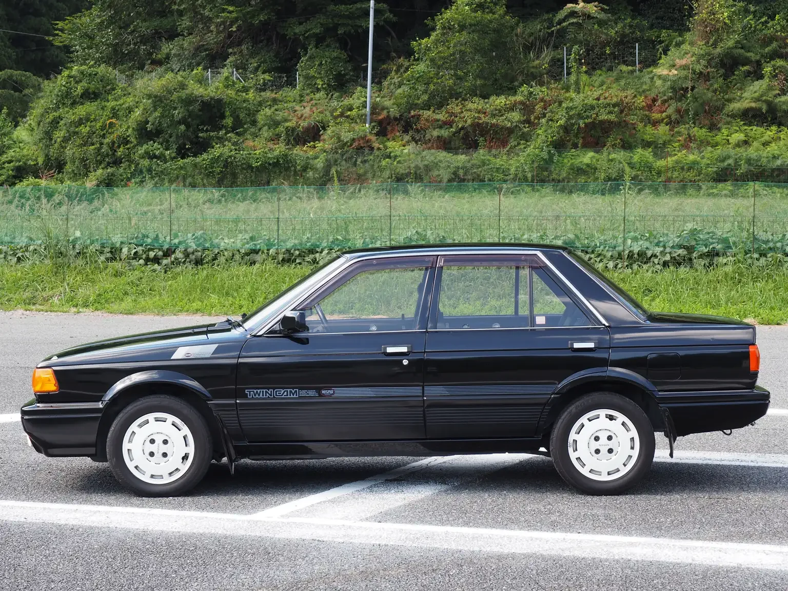 passenger side view of 1989 Nissan sunny super saloon twin cam NISMO in black jdm export vehicle Japan