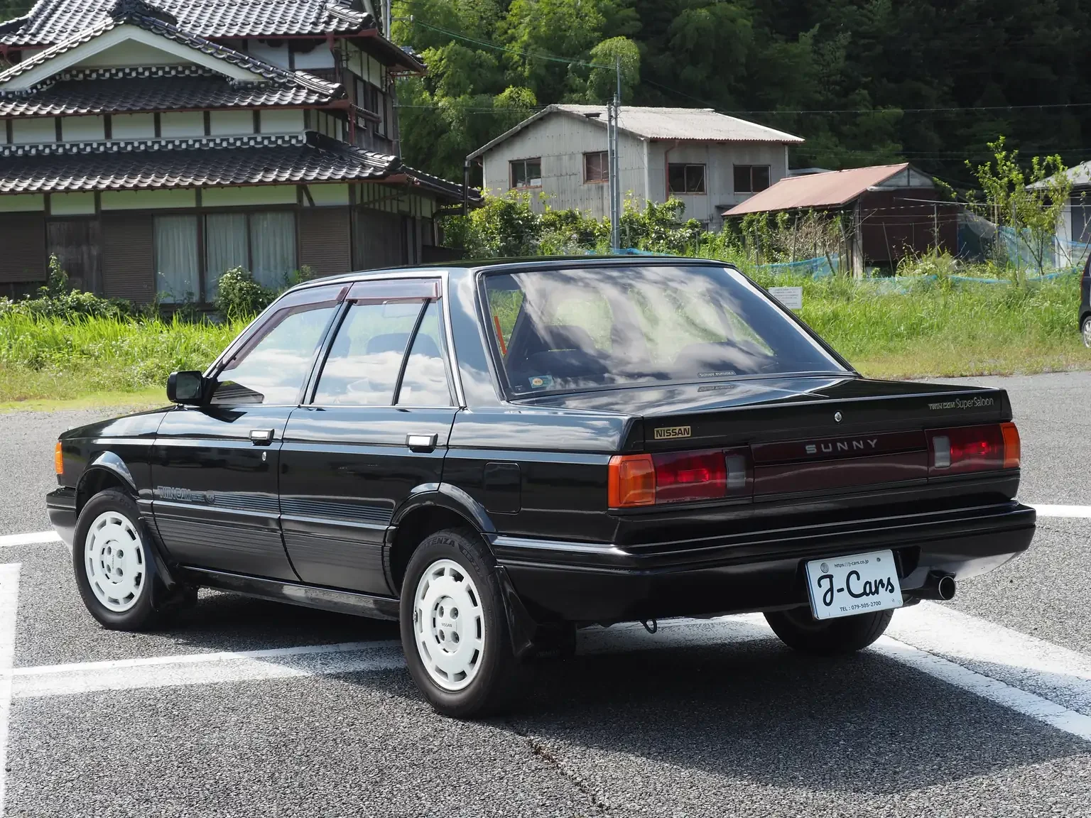 rear passengers angle view of 1989 Nissan sunny super saloon twin cam NISMO in black jdm export vehicle Japan