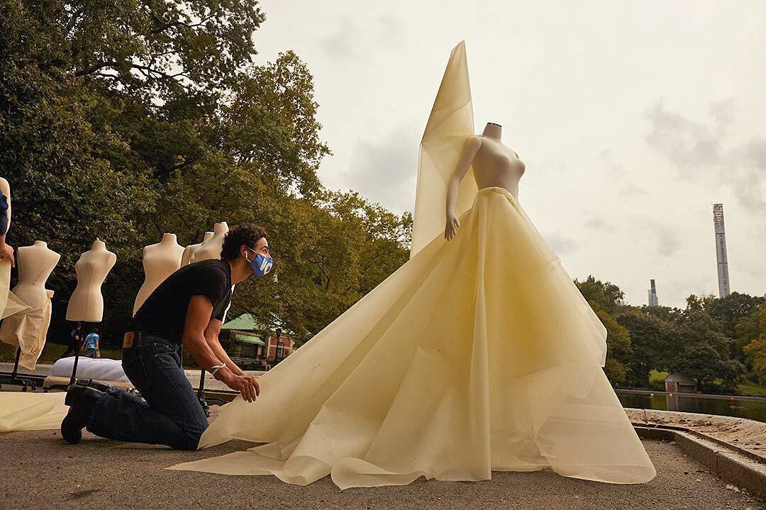 Zac Posen drapes dresses on mannequins in Central Park in NYC for September Fashion Week in a VOTE mask