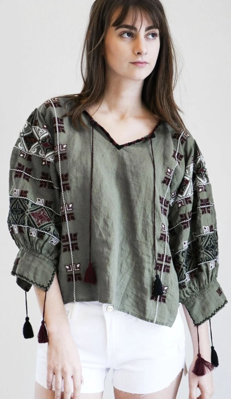 Nili Lotan women's green and white blouse (2006–2007 collection), listed on Depop and eBay with a description noting "geometric embroidery", yet no reference to its clear Palestinian origins.