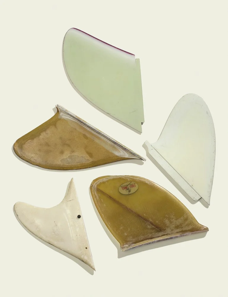 Clockwise from top: a late ’60s “D” fin with foiled edge; a late ’60s “D” fin; an early ’60s Greg Noll “Chop Stick” fin; an early prototype fin for rental boards in Waikiki (note the side screw for mounting); a late ’50s Greg Noll big wave fin.