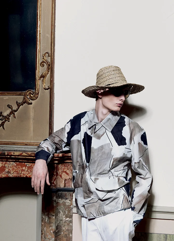 Slate coated canvas blouson, cotton shirt, and linen one-pleat trousers HERMÈS sunglasses PERSOL