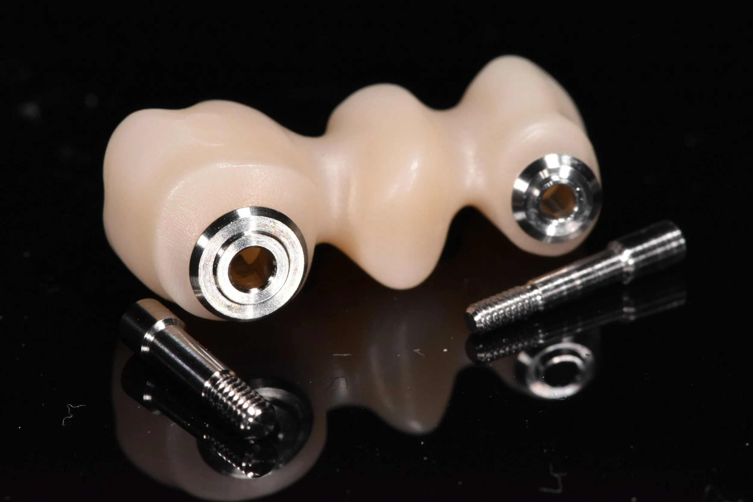 Zahnimplantat mit Metallgewinden auf schwarzem Hintergrund