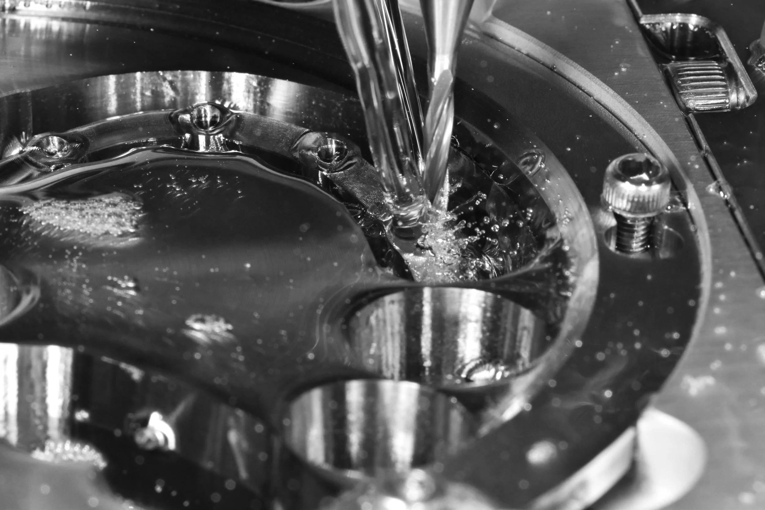 Nahaufnahme eines Metallbearbeitungsprozesses mit einer Fräsmaschine, die kühlschmierstoffumgeben gebohrt wird.