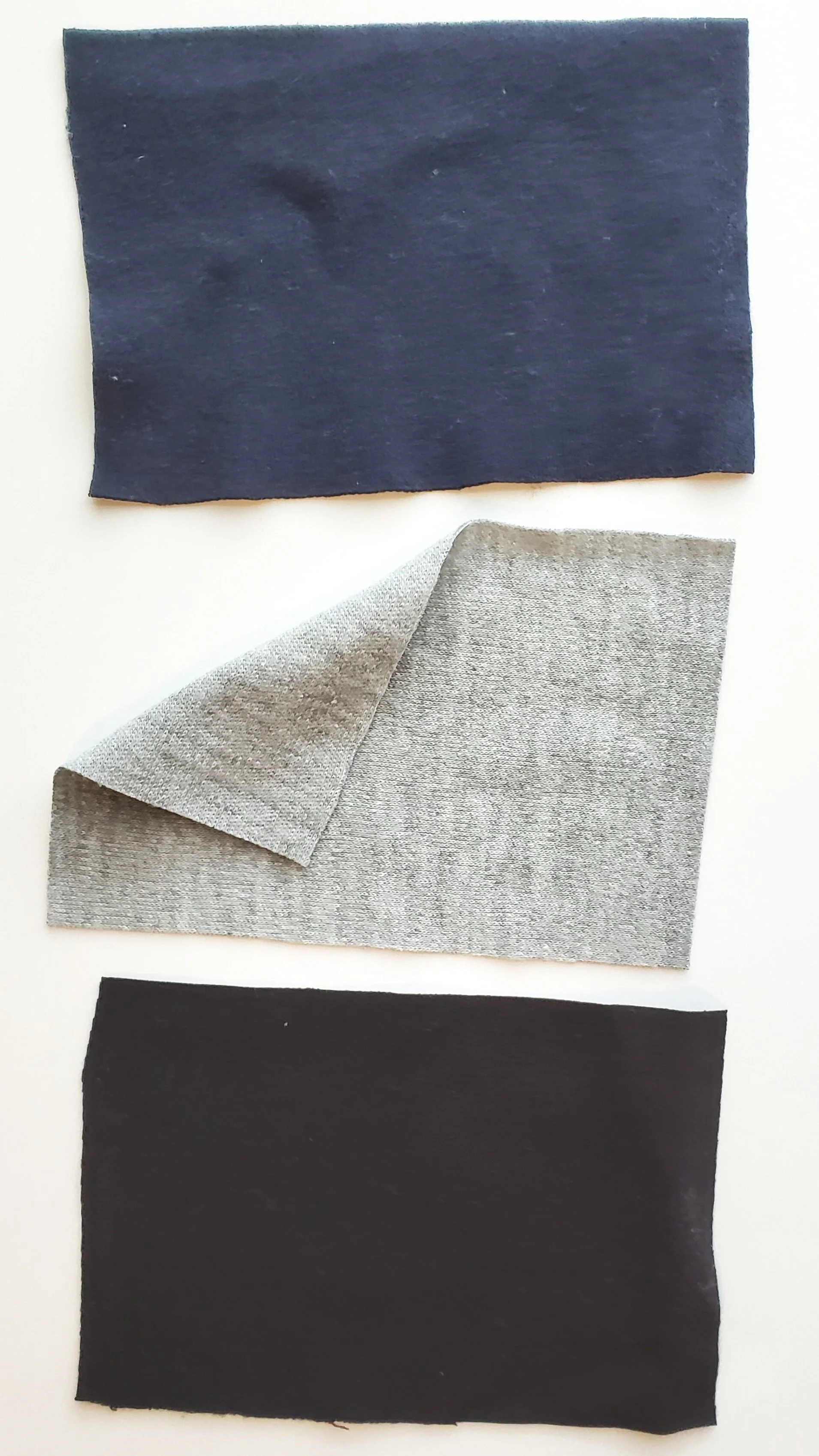Top to bottom: navy double knit, grey Interlock knit, black Ponte. The navy double knit and black ponte have a very fine knit structure that gives the fabric a smooth, monolithic appearance.