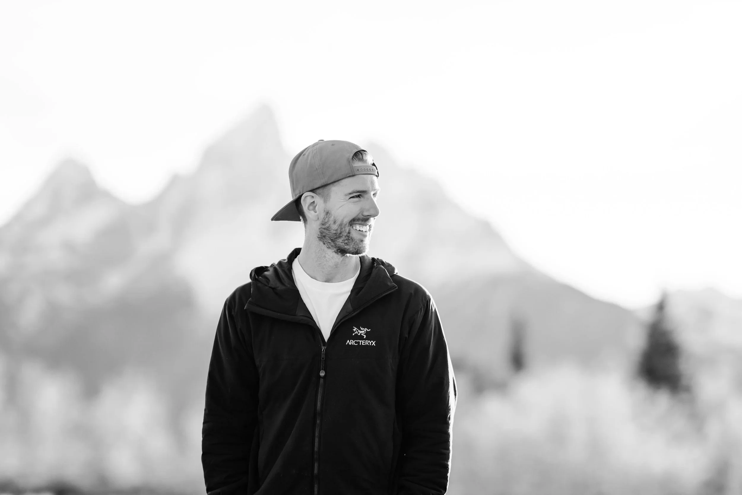 Photo of Denver Photographer Tim Gillies in the mountains with a backwards hat on and outdoorsy jacket.