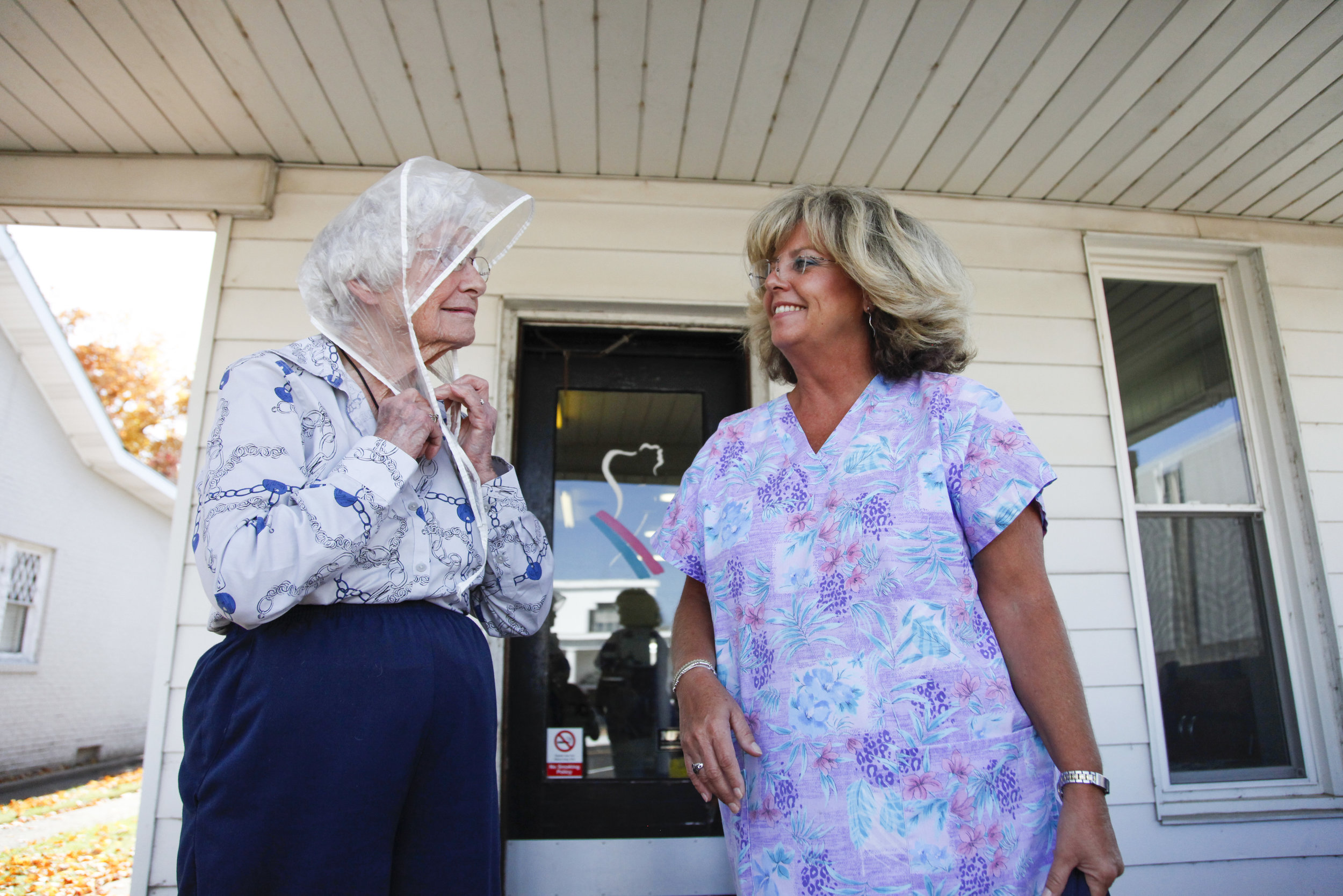   Kelly Alvey, (right), holds Gladys Luck's purse as she puts her rain scarf on after receiving her weekly hairdo at Kelly's Mane Event. Because 90-year-old Gladys has walking difficulties, Kelly assists her when she leaves the salon.     