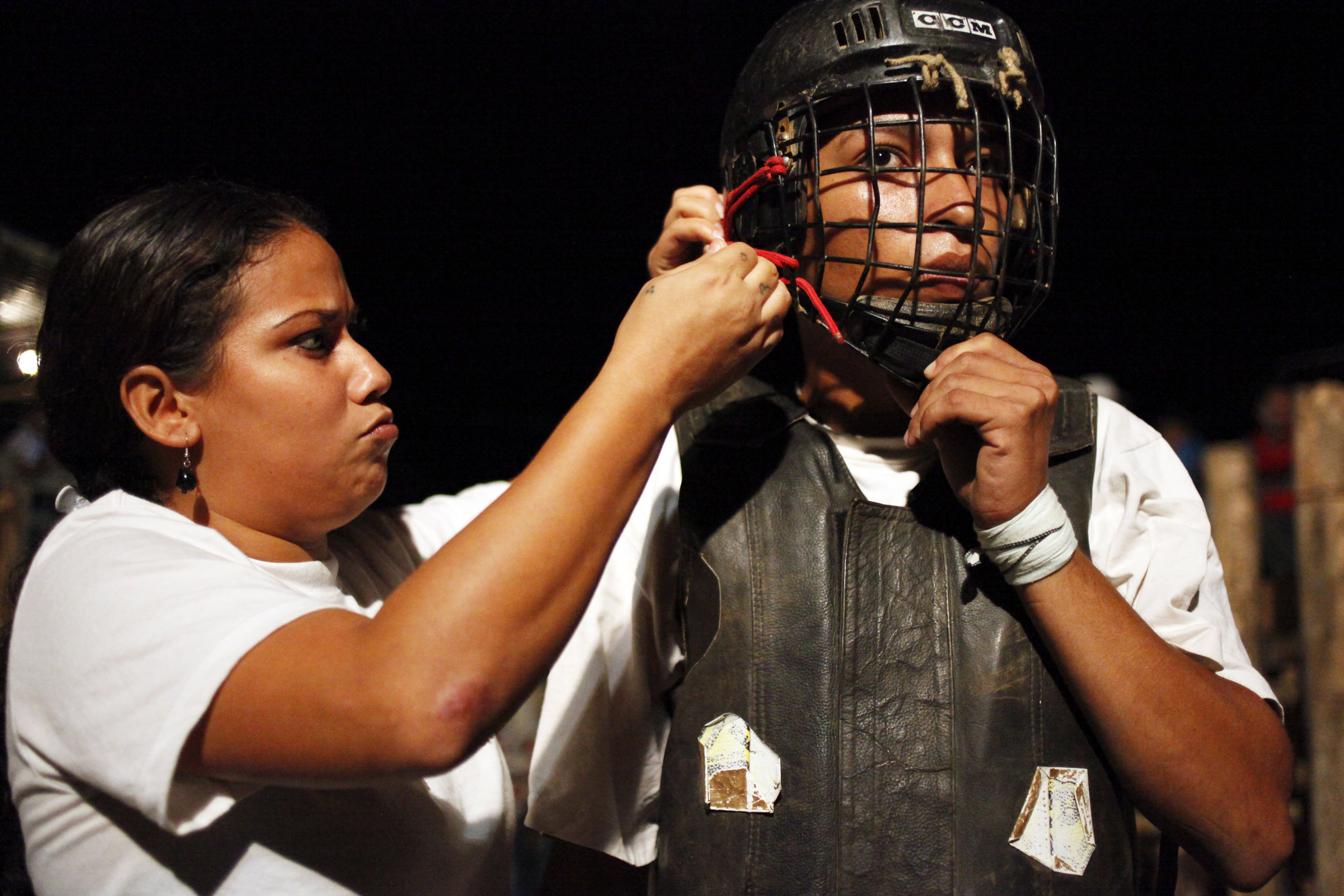  Eveling Peréz, a Nicaraguan bull rider, left, helps Rafael Guevara put on his helmet before his turn starts during the first night of the bull run at the Nosara Fair of 2013 in Costa Rica.     