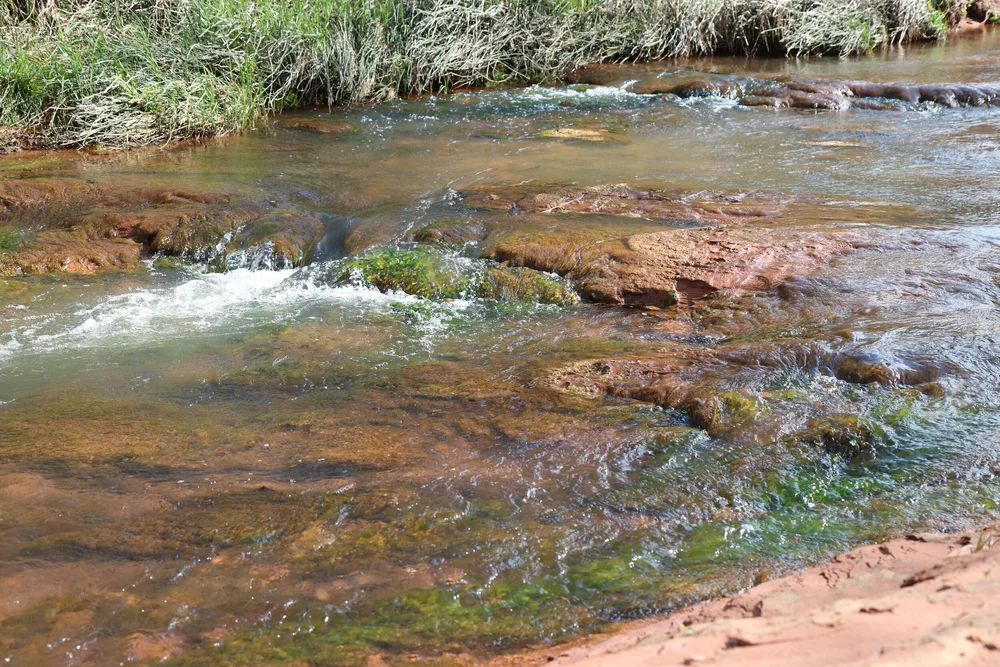 A clear creek running over red rock