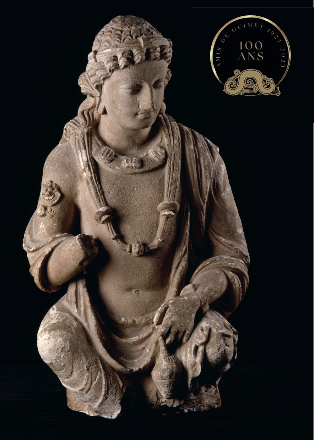 Statue ancienne représentant une figure féminine en pierre, avec des bijoux et des vêtements traditionnels, commémorant le centenaire des amis de Guimet en 2023.