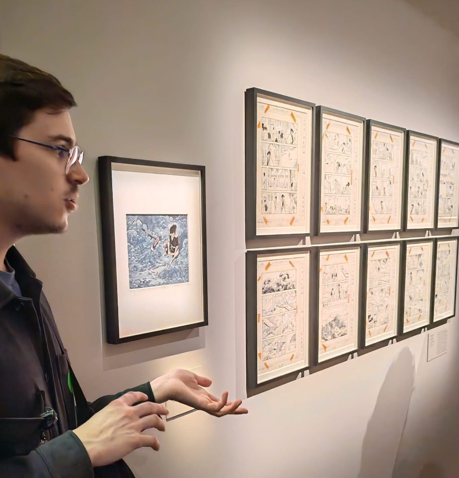 Un homme regarde une série de bandes dessinées exposées dans une galerie d'art.