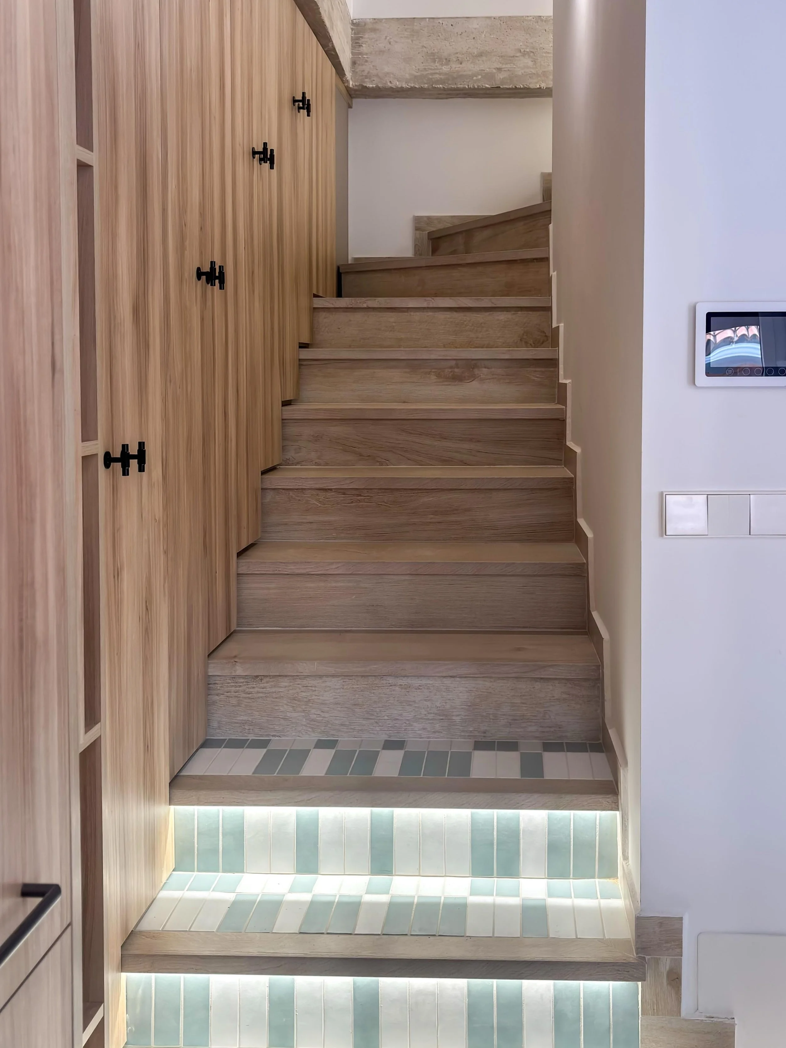 La combinaci&oacute;n entre madera natural, iluminaci&oacute;n indirecta y detalles azul 
verdoso aporta profundidad y personalidad a esta escalera dise&ntilde;ada a medida.

Cada material fue seleccionado para integrarse con la arquitectura de la vi