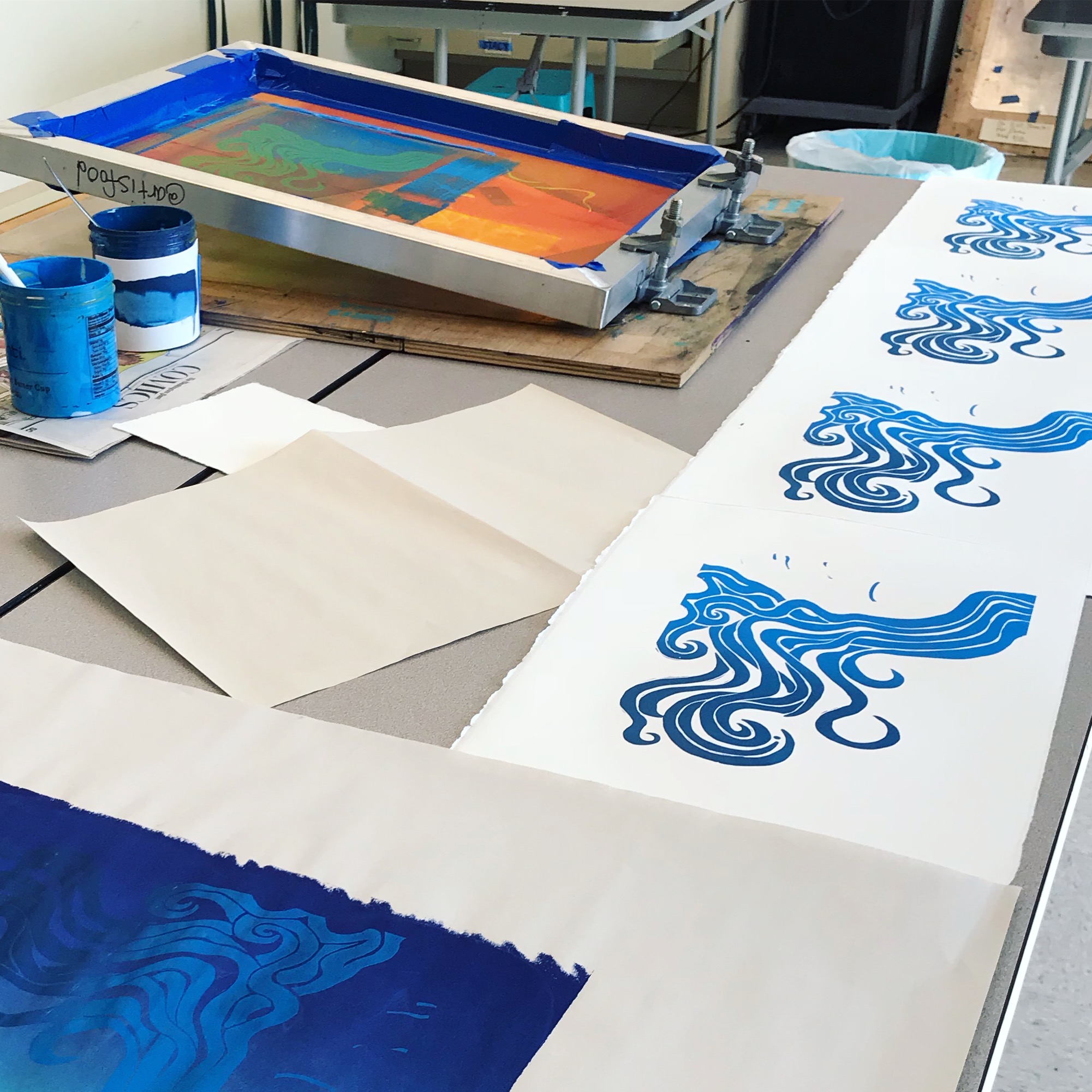 Screenprinting studio with blue ink and fresh blue wave prints.