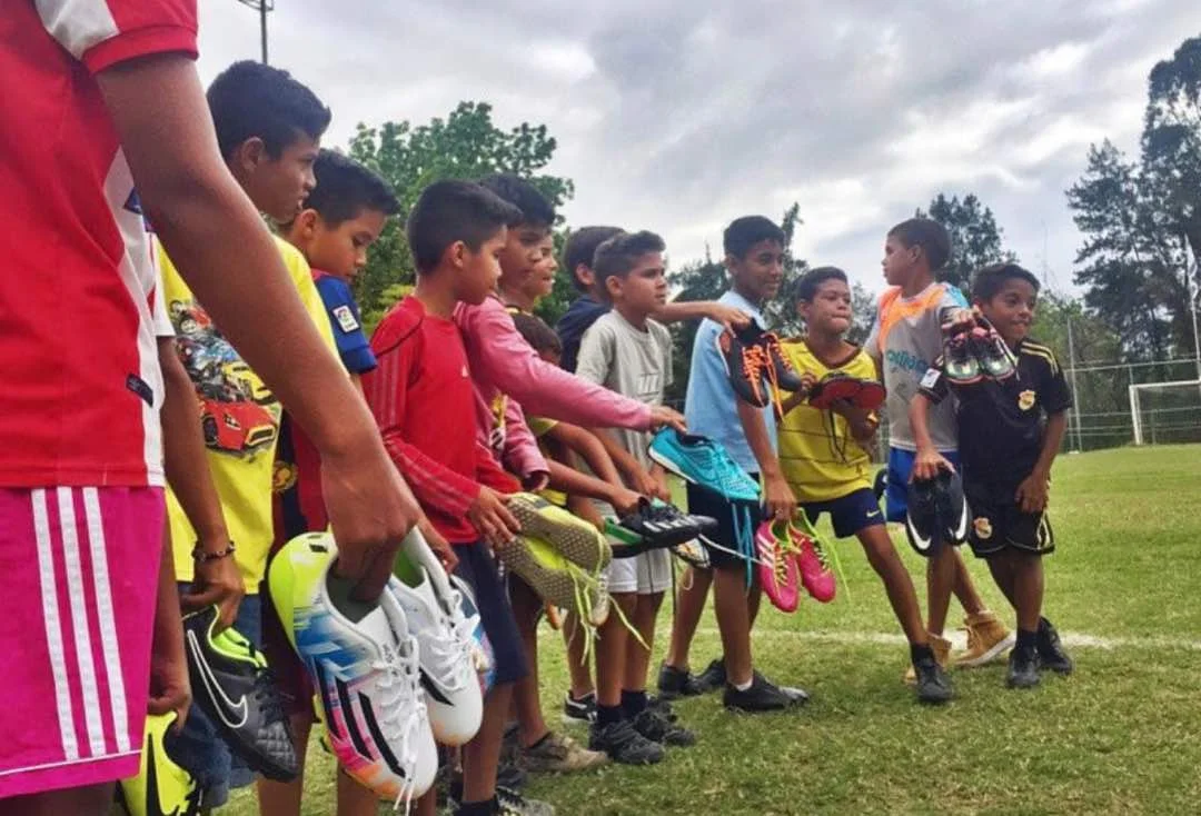 Boys at the sports centre huddle up before a game of football, holding their new sneakers courtesy of the A Pair for a Dream foundation. (Photo Credits: A Pair for a Dream)