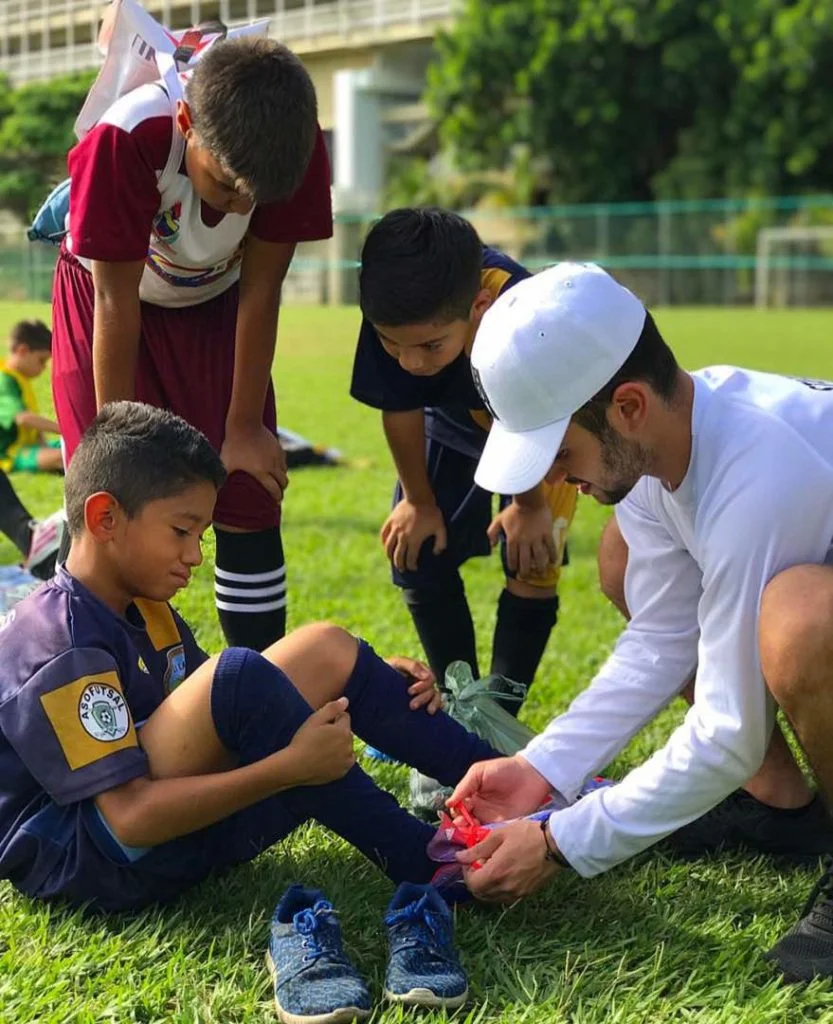 Eithan Fincheltub helps a boy try on sneakers donated by his foundation, searching for the perfect fit. (Photo Credits: A Pair for a Dream)