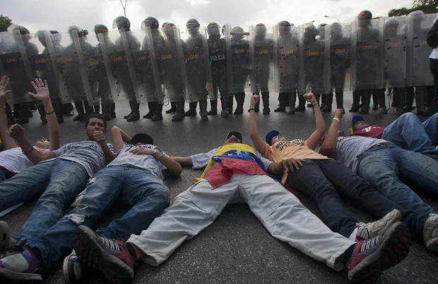 Simpatizantes de la oposición venezolana protestan frente a los policías antidisturbios en Caracas el 15 de abril de 2013. (AFP PHOTO/Geraldo Caso)