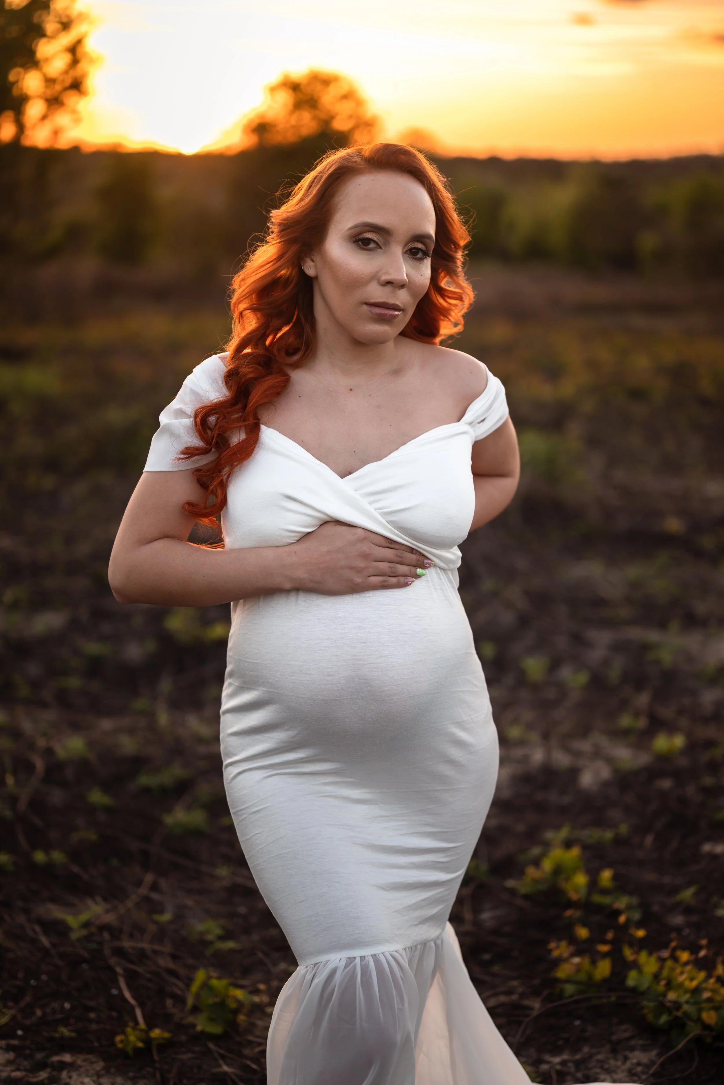 pregnant-woman-holding-belly-sunset-field-florida-maternity-portraits.jpg