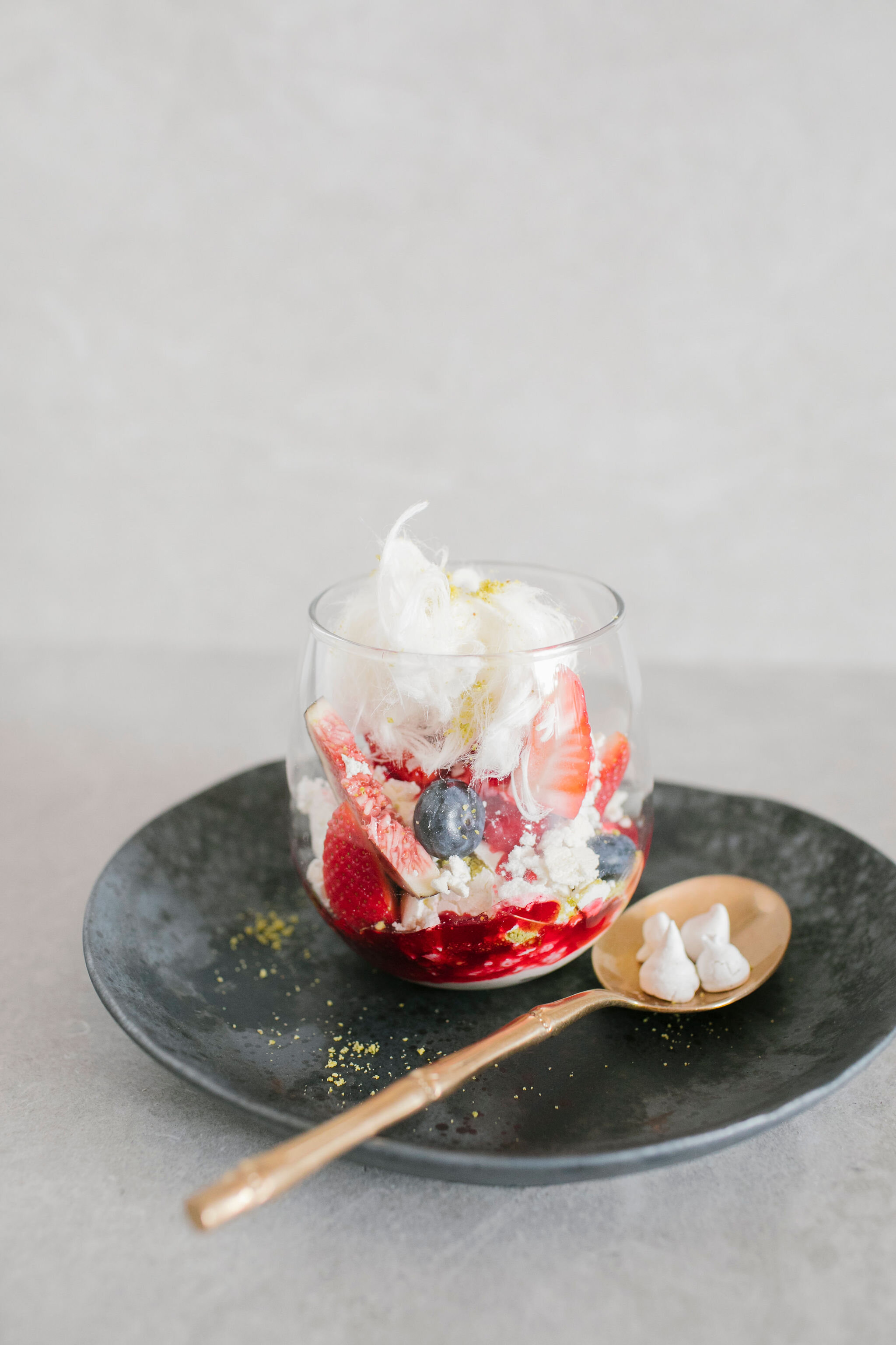Eton mess in a glass with summer fruits in berry coulis, black fig and pistachio fairy floss plated.jpg