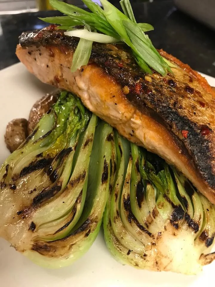 Crispy skin salmon with a spicy Korean chili butter over grilled bok choy