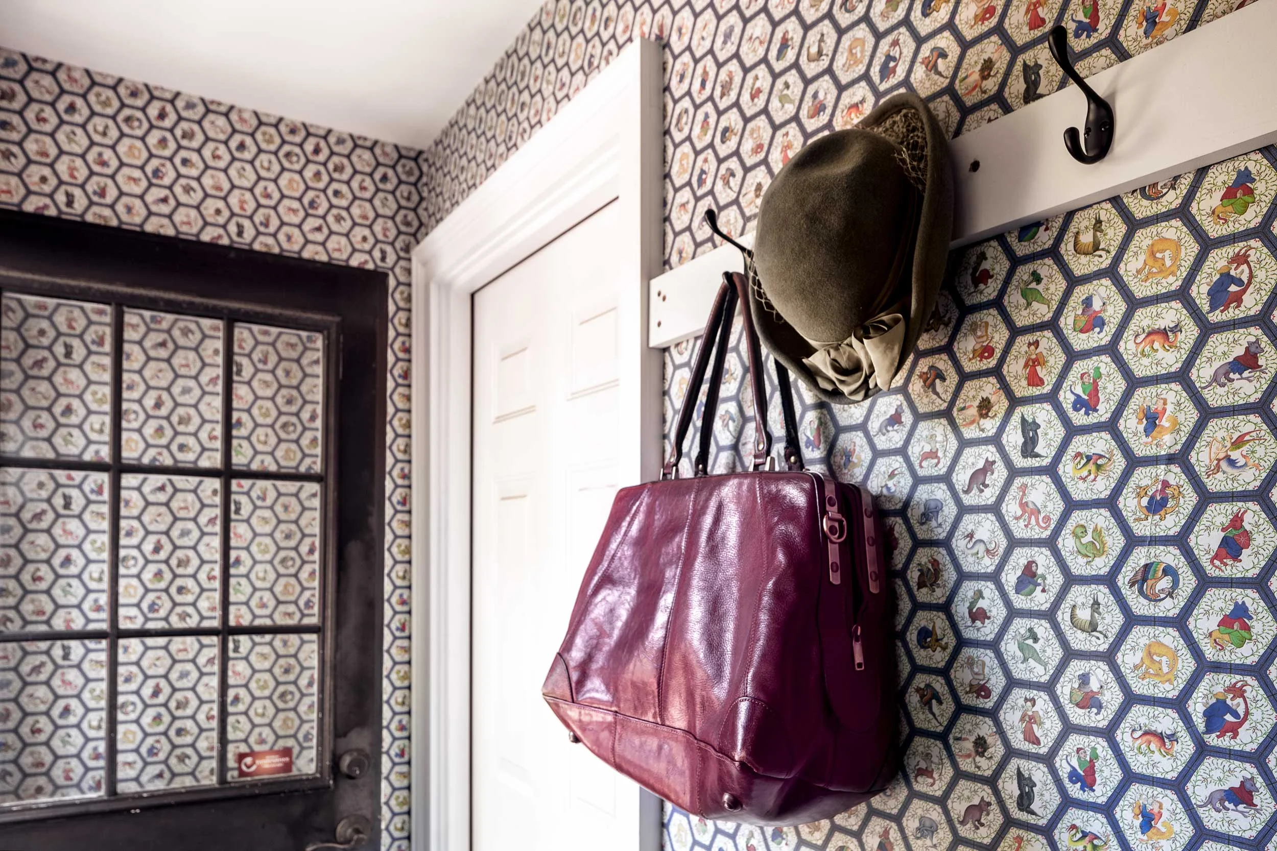 Saiber typed “medieval or Renaissance wallpaper” into a search engine and discovered Spoonflower, which produces custom wallpaper. They picked a design for their back hallway that incorporates monsters from medieval manuscripts. The red bag is from Spain, and the hat is one of several Saiber inherited from her grandmother.