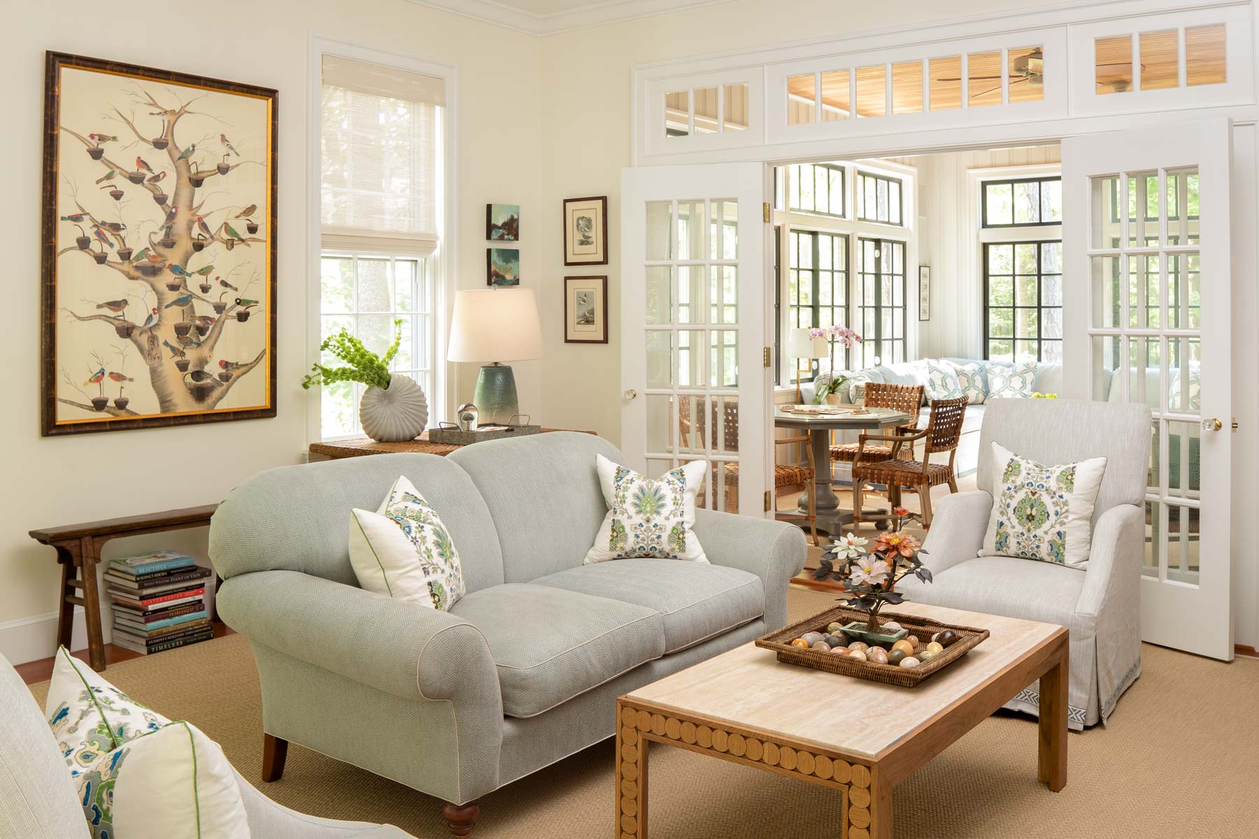 The living room has fifteen small framed Audubon prints, all of birds of Maine. The homeowners wanted another bird picture that wasn’t an Audubon for the space. Fremont-Smith sourced the tree with birds, a large watercolor on silk, at Hurlbutt Designs. The room is entirely open to the neighboring sunroom but is still defined by clerestory windows and French doors. A turret space with built-in seating is just out of view to the left.