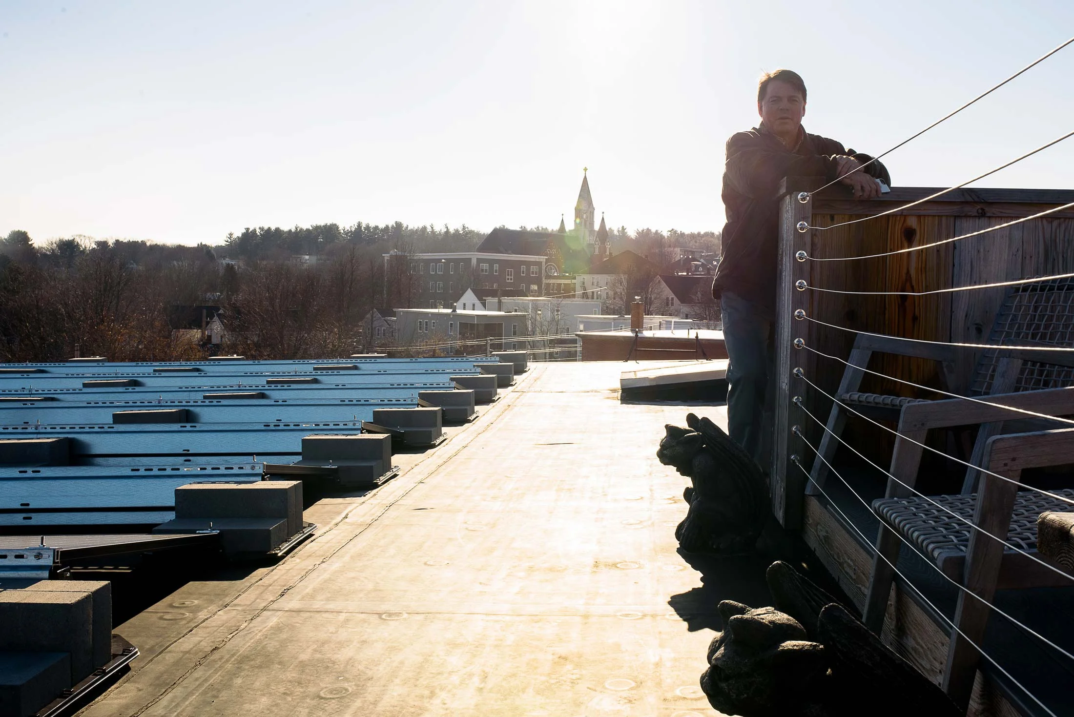 Scott Joslin, COO of the Pepperell Mill Campus, stands on the roof beside the solar array installed by ReVision Energy. Beyond, a bird’s eye view of downtown Biddeford.