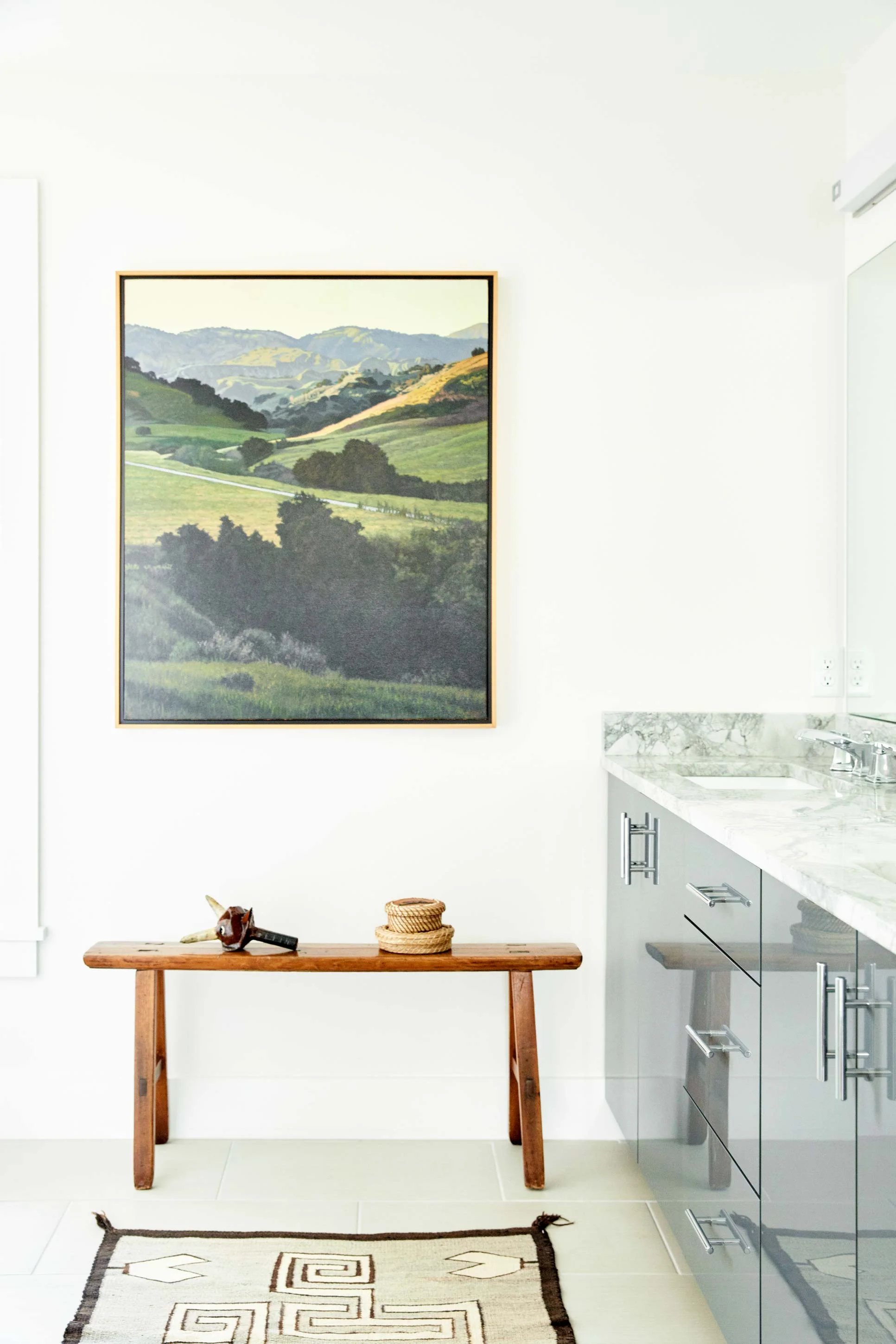 A curated spot in the master bath features a painting by Bruce Everett over a French nun’s prayer bench from the late 1700s. On the bench is a Krampus by E. Michael Contreras and two Wabanaki baskets topped with porcupine quills. A circa-1920s Navajo weaving completes the look.