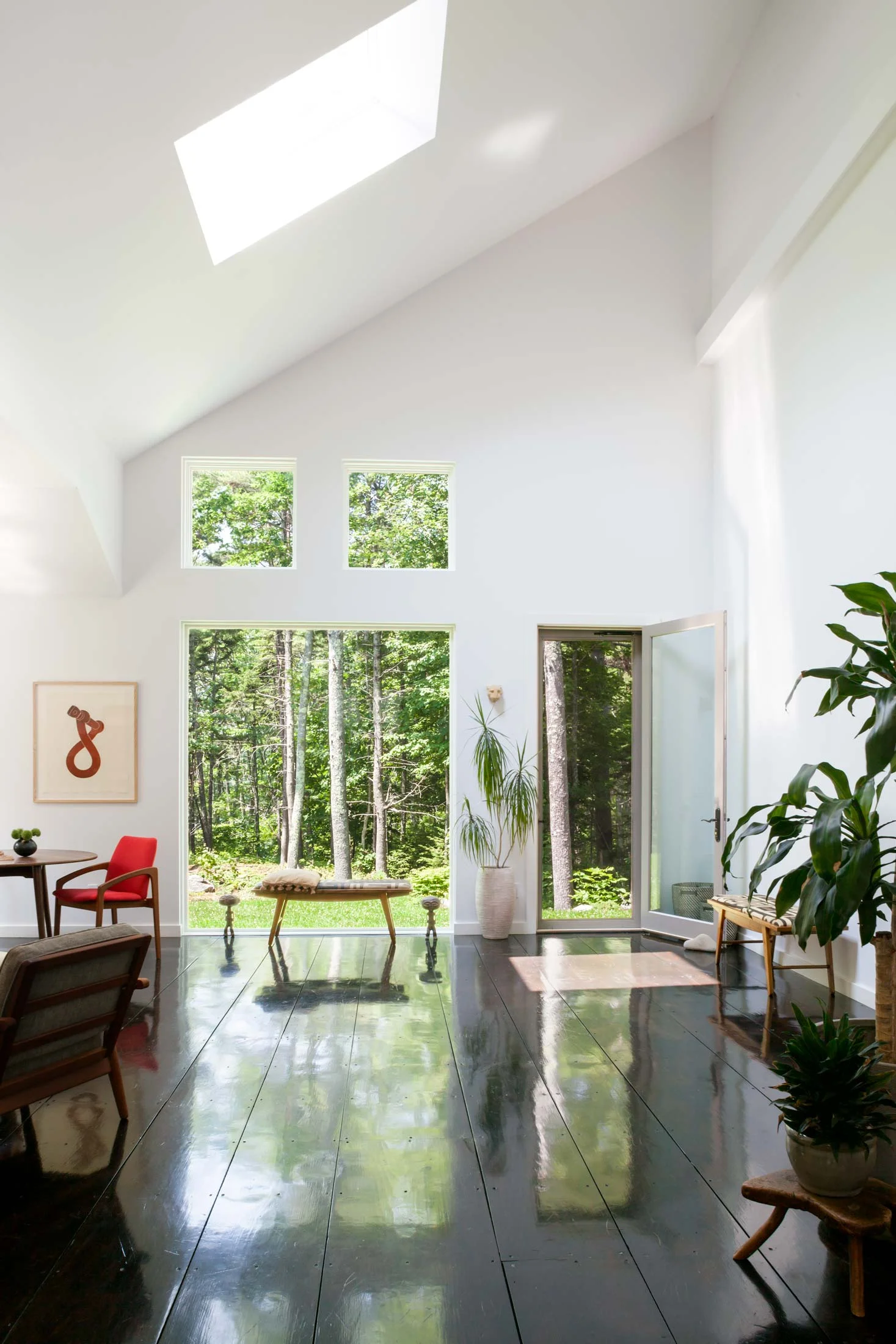 When you walk through the front door and turn left, the view is of this open hallway with a minimalist floating staircase to the right and living room to left. The picture of a twisted boat shackle is from James Dodd and was acquired at Dowling Walsh Gallery. The benches are covered with Congolese fabric. Between the square windows, skylight, and large picture window, the house needs no artificial light during the day.