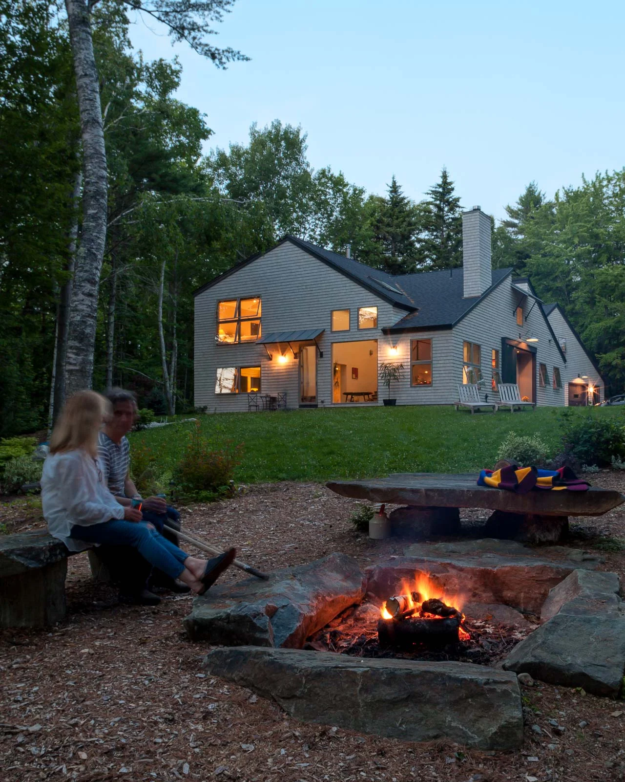A view from the firepit up to a side of the house that shows the shape of the original roof and the square windows that are part of the purposefully limited vocabulary of the house.