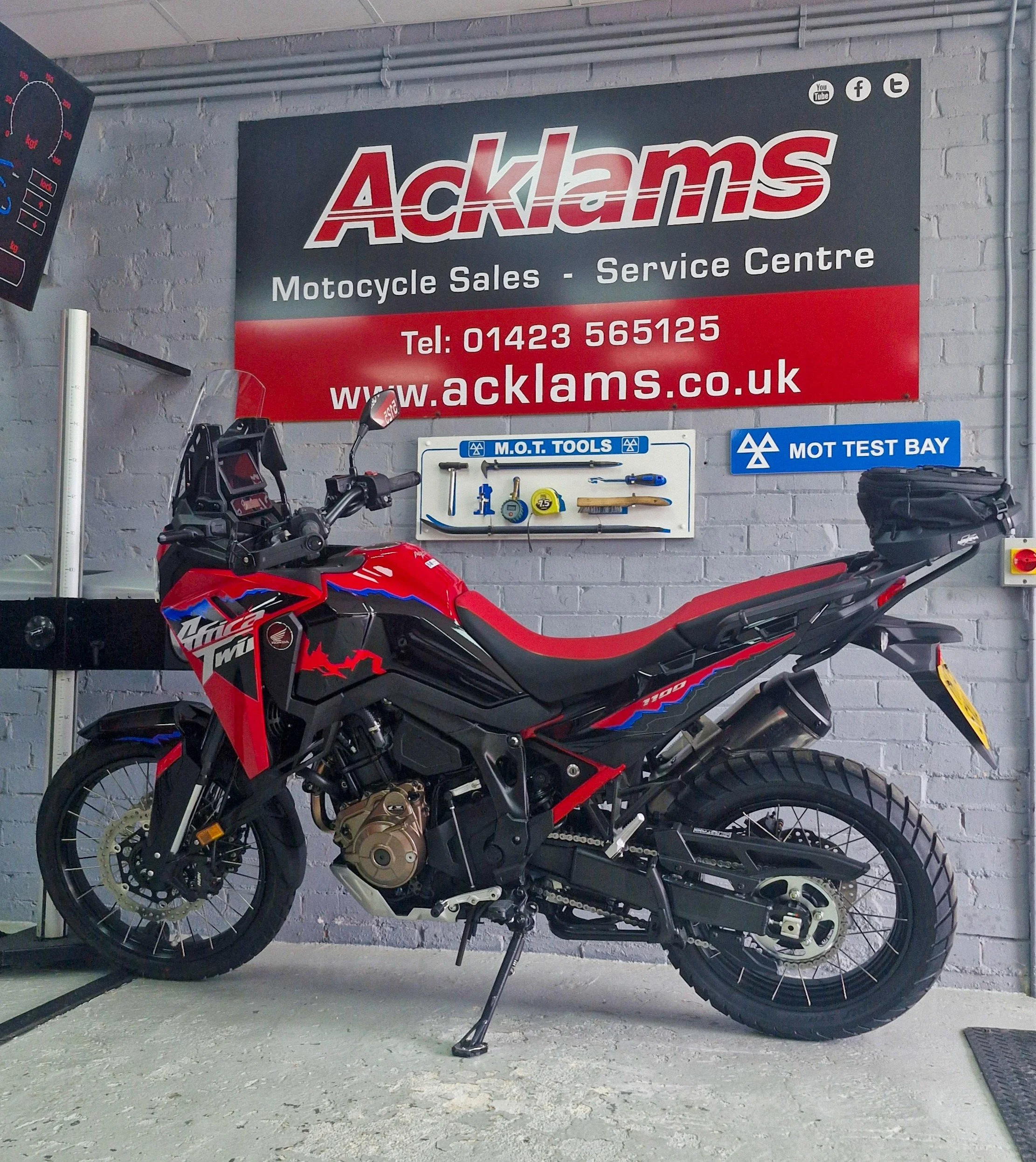A Honda Africa Twin in red and black parked inside the workshop, mid- MOT