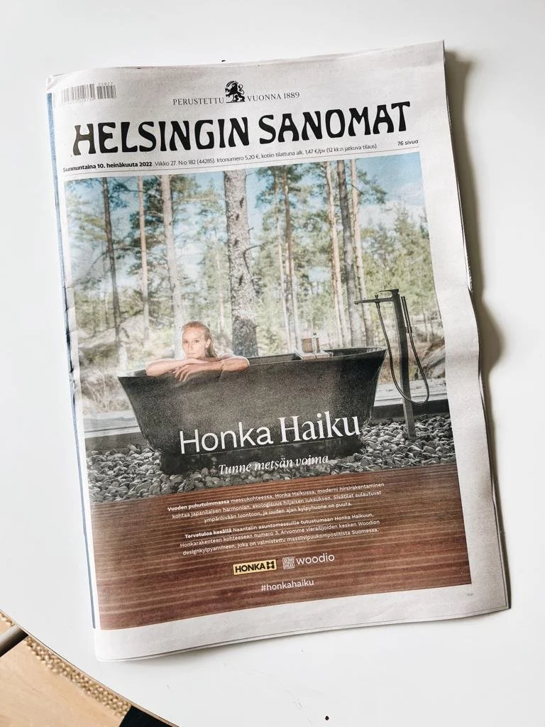 Helsingin Sanomat -lehden etusivu, jossa on mainos Honka Haikusta. Kuvassa näkyy henkilö kylvyssä ulkona luonnon keskellä, taustalla puita. Mainosteksti: 'Honka Haiku - Tunne metsän voima'. Julkaisupäivämäärä on sunnuntai 10. heinäkuuta 2022. Mainos mukana tuotemerkkejä Honka ja Woodio, sekä hashtag #honkahaiku.