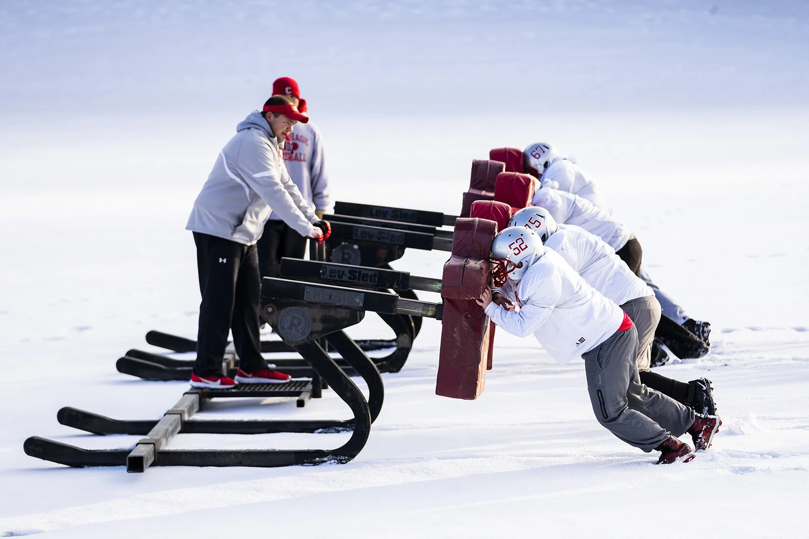  Members of the Carthage Comets offensive line push the training sleds through the snow during a late November practice as they prepare for the playoffs. 