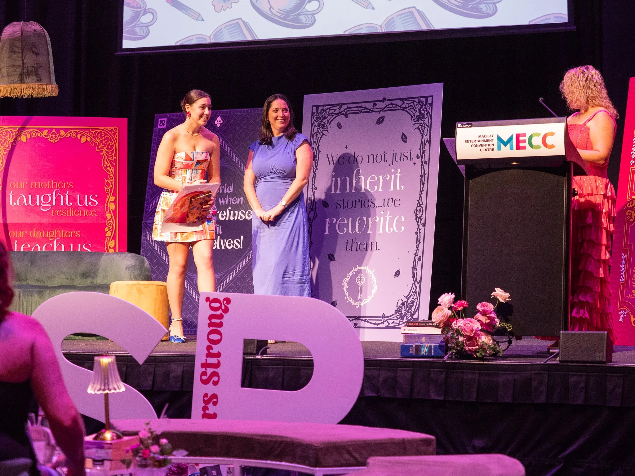 A landscape with snow-capped mountains in the background and a modern building on a grassy hillside in the foreground.