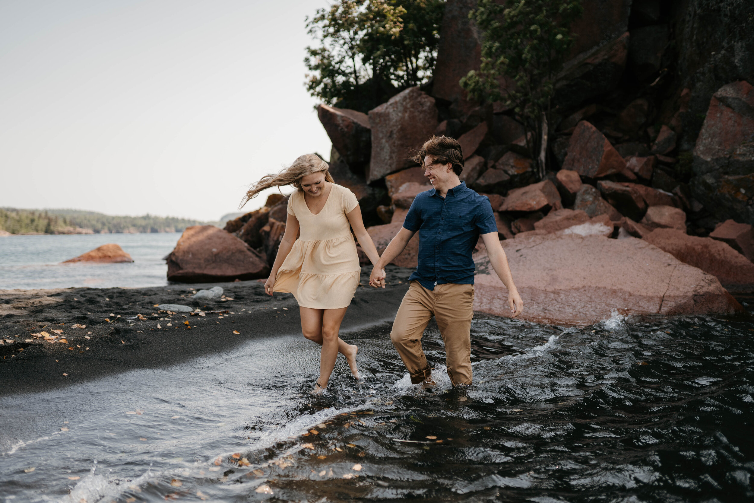 Engaged couple walking in the water at black sand beach